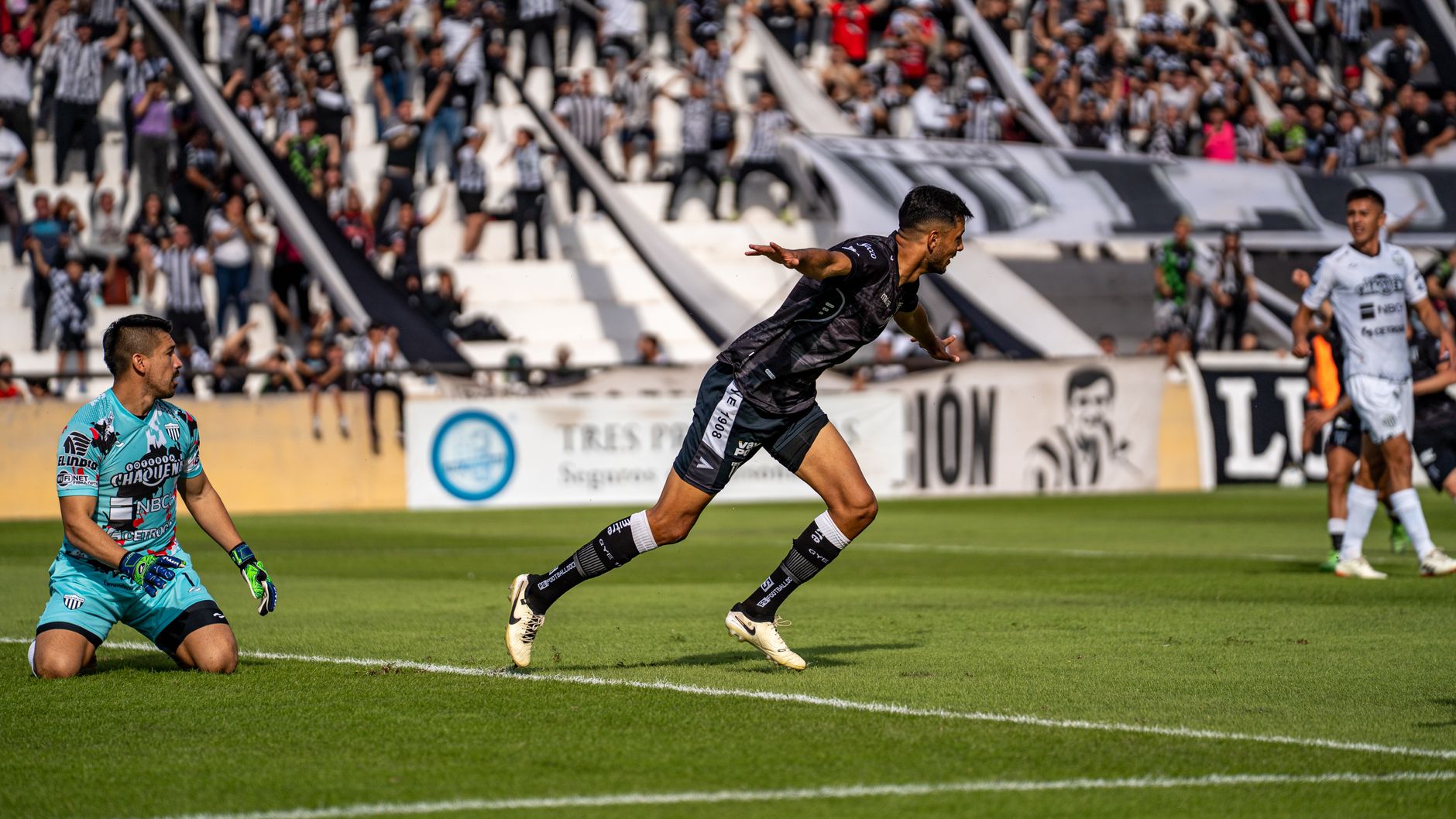 Intense soccer match with player celebrating goal in front of excited crowd.