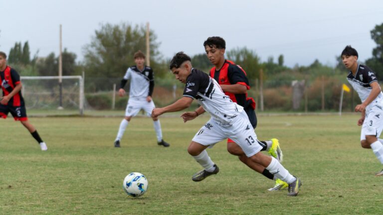 Young athletes in a competitive soccer match, showcasing agility and teamwork on a grassy field under a cloudy sky.