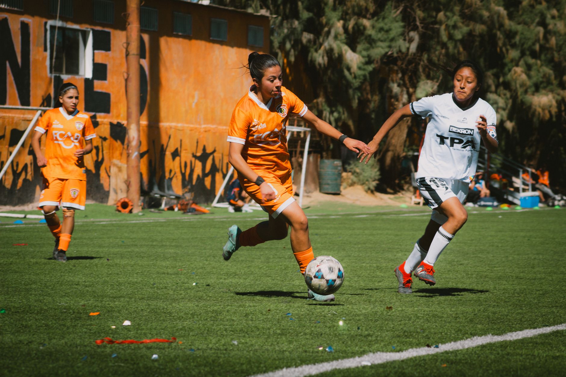 Exciting women's football match with players in action on a sunny day in Chile.