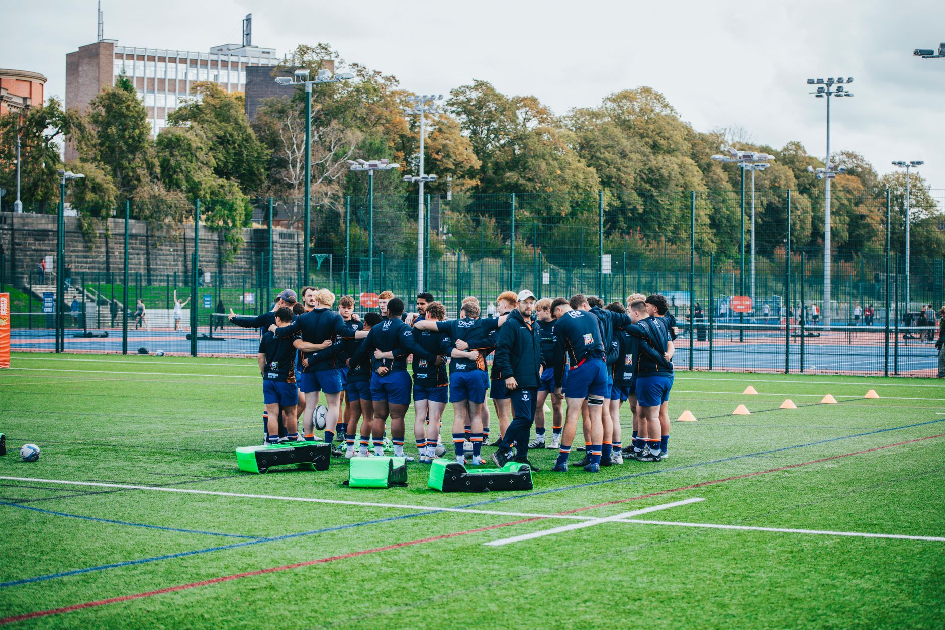 Team of rugby players huddling during outdoor training session on a sports field.