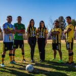Seven athletes in football gear team photo on sunny field