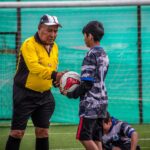 An adult coach and young players during a soccer practice session outdoors in Chile.