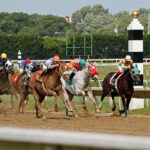 Thrilling shot of jockeys racing on horses around a bend at a vibrant horse racing event.