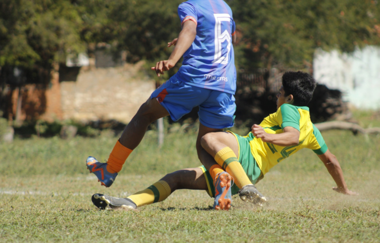 Two teenage soccer players in action on an outdoor field, competing fiercely.