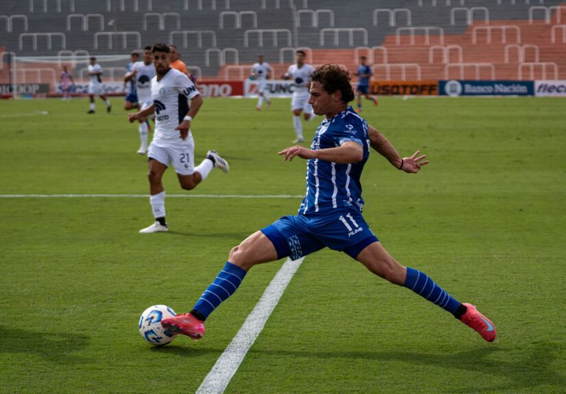 Dynamic soccer match featuring players in blue and white uniforms during a sunny day.